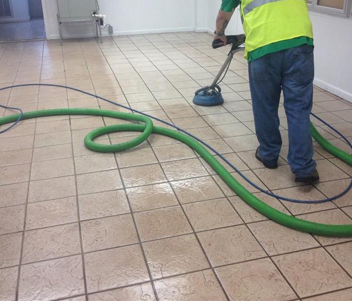 tile with dark discoloration and a SERVPRO worker cleaning the floor