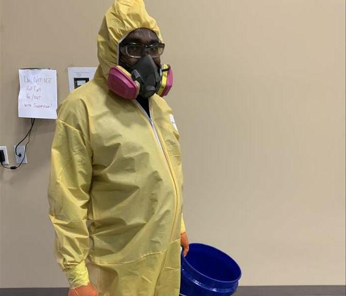 Technician in PPE holding a bucket