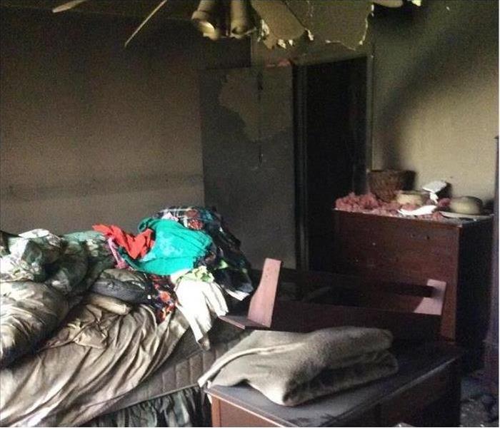 Burned bedroom, walls covered with soot, clothing on bed