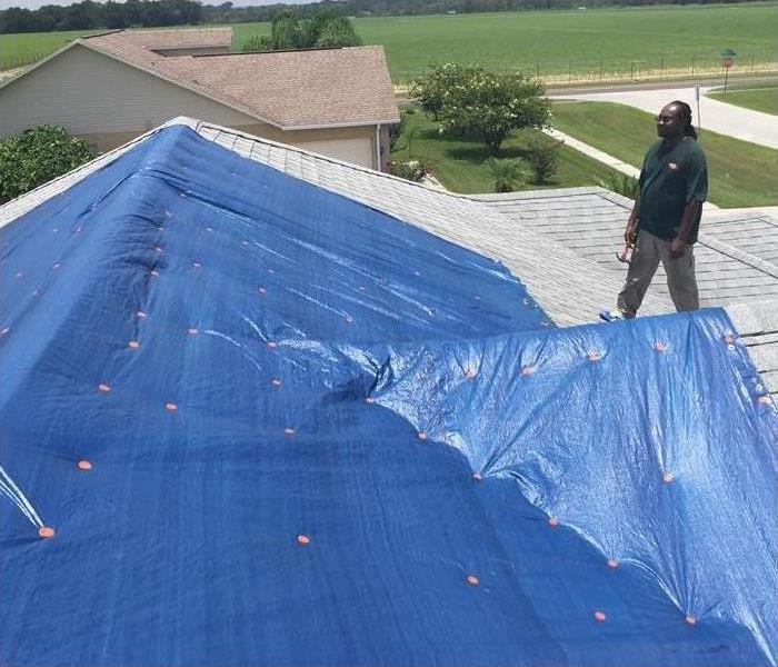 Blue tarp on roof, man on roof